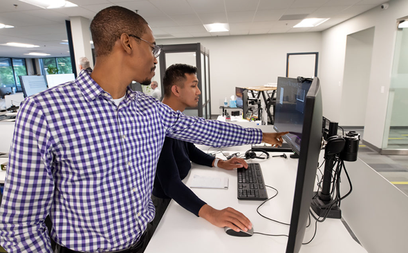 Two coworkers reviewing data on monitor